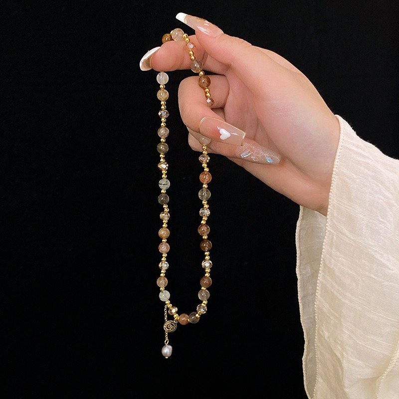 Long natural stone beaded bracelet with gold-tone accents and charm detail