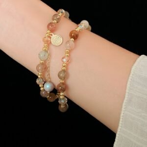 Gold-tone crystal charm wrap bracelet styled as a layered bracelet on wrist