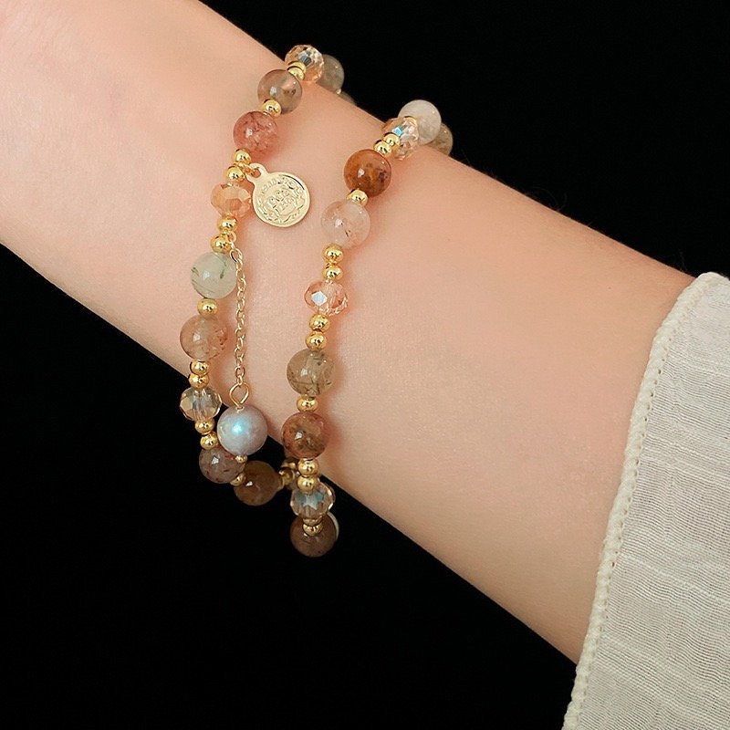 Gold-tone crystal charm wrap bracelet styled as a layered bracelet on wrist