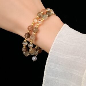 Layered natural stone beaded bracelet worn on wrist with gold-tone charm